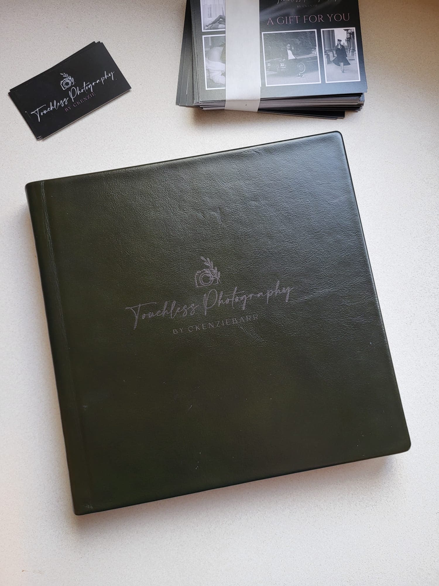 A dark green leather album cover with the Touchless Photography mark